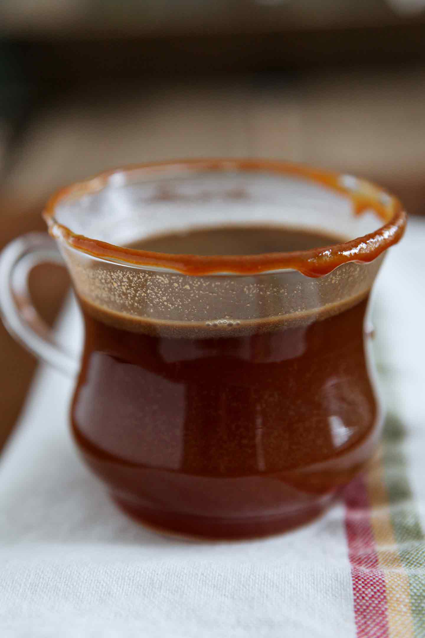 A glass of Spiked Apple Cider sits on a wooden serving tray