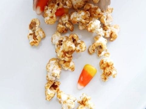 Popcorn and candy corn spilling out of bowl onto white plate