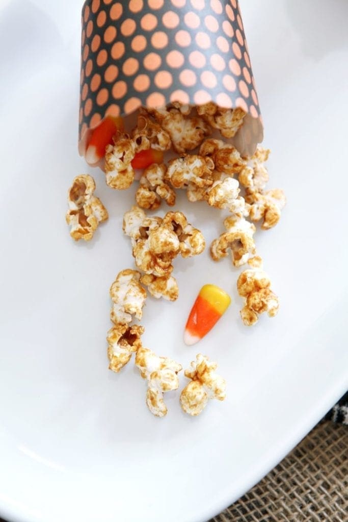 Popcorn and candy corn spilling out of bowl onto white plate 