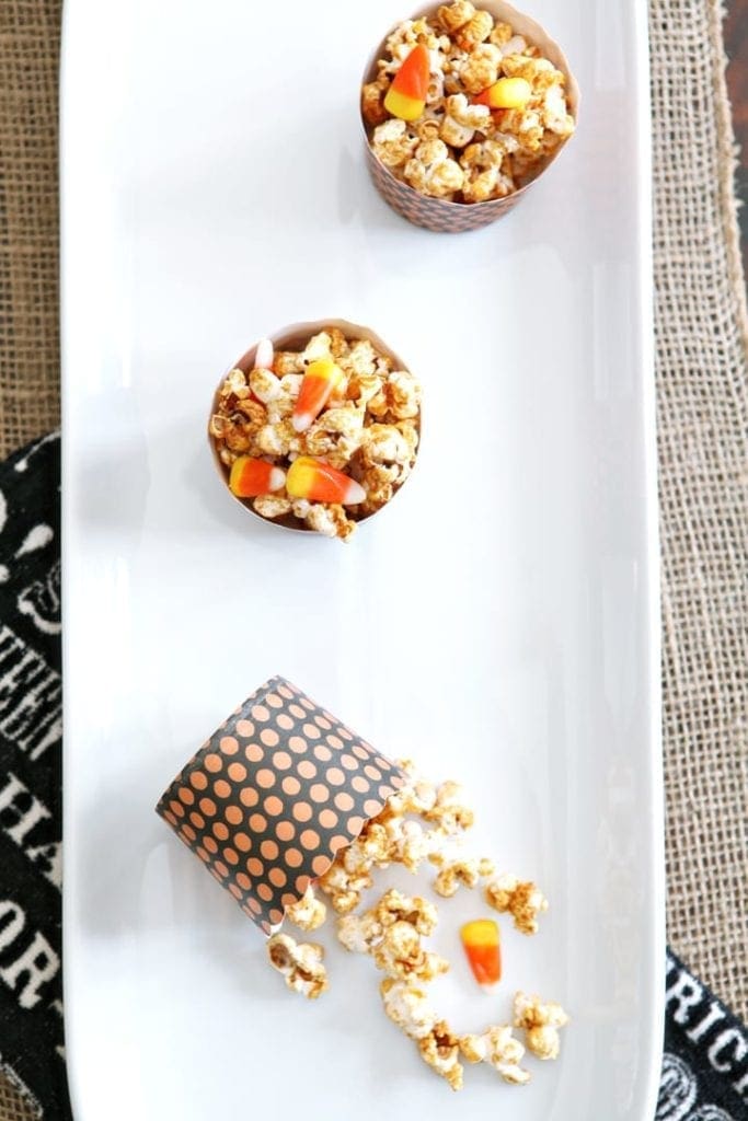 Overhead view of popcorn with candy corn in bowls on white serving dish 