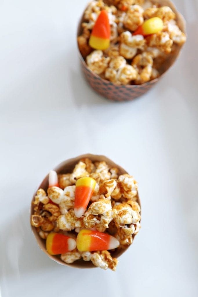 Cups of Halloween Caramel Corn sit on a white platter