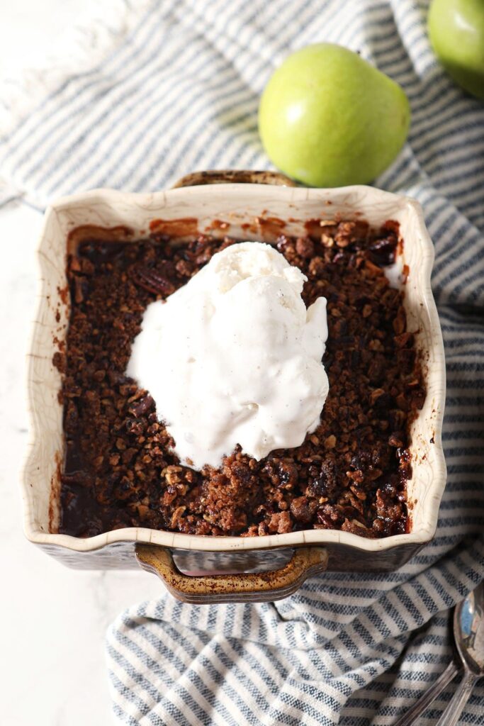 A square casserole of apple crumble with ice cream on top