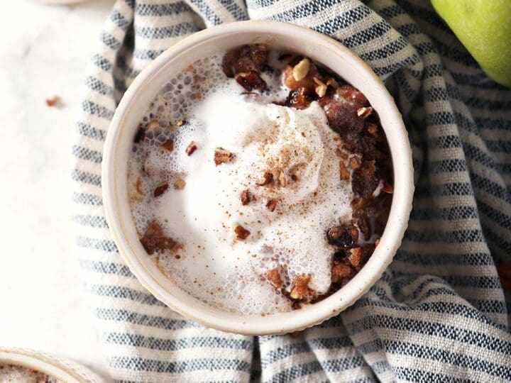 Close up of a bowl of apple crumble with ice cream on top