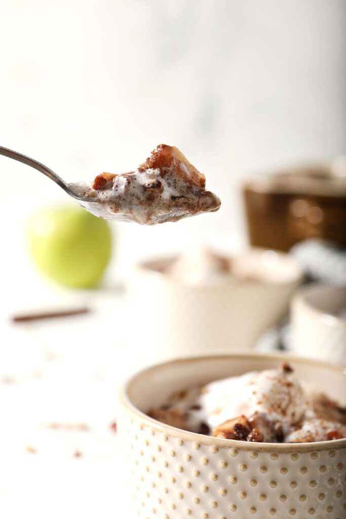 A spoon holds a scoop of an apple crumble recipe above a bowl