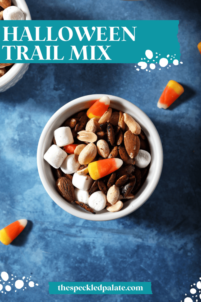 A small bowl of trail mix with nuts, candy corn and marshmallows with the text halloween trail mix