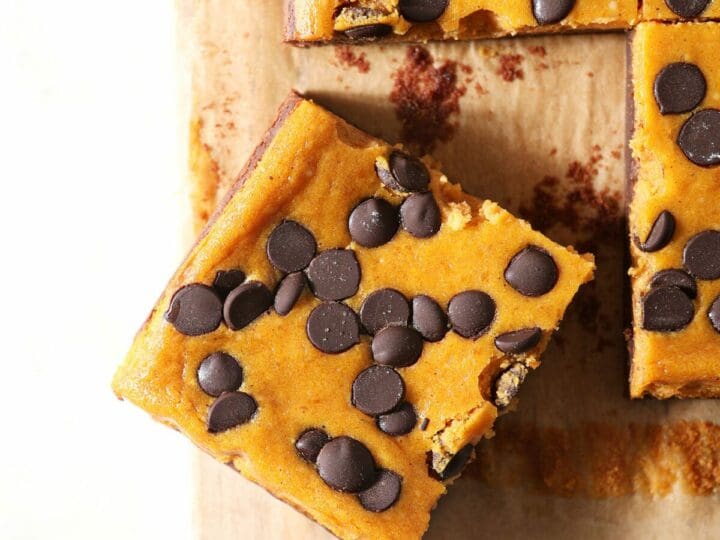 A sliced Pumpkin Cheesecake Bar on a wooden board with other bars