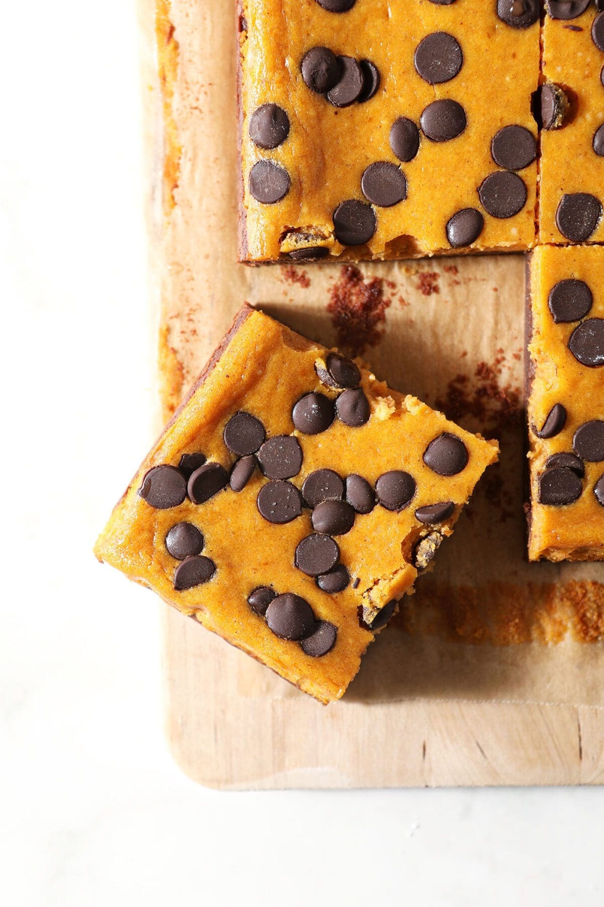 A sliced Pumpkin Cheesecake Bar on a wooden board with other bars