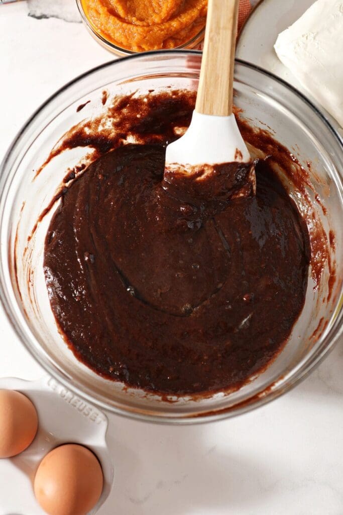 The brownie base is stirred by a rubber spatula