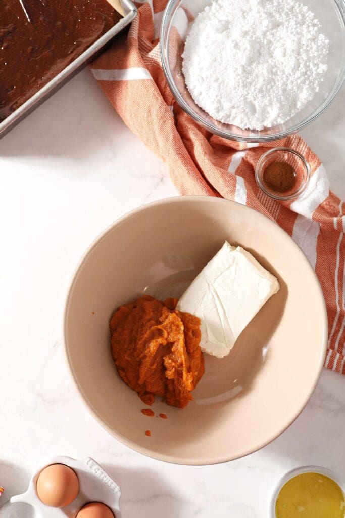 Pumpkin puree and a cream cheese block in a bowl