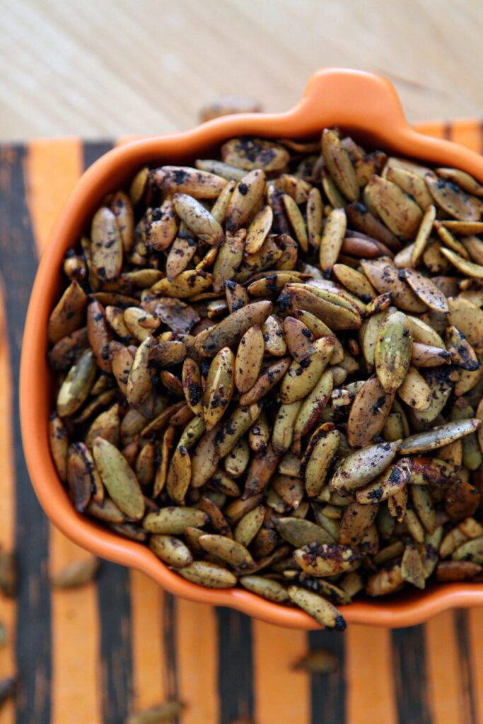 Close up of an orange bowl of roasted pumpkin seeds