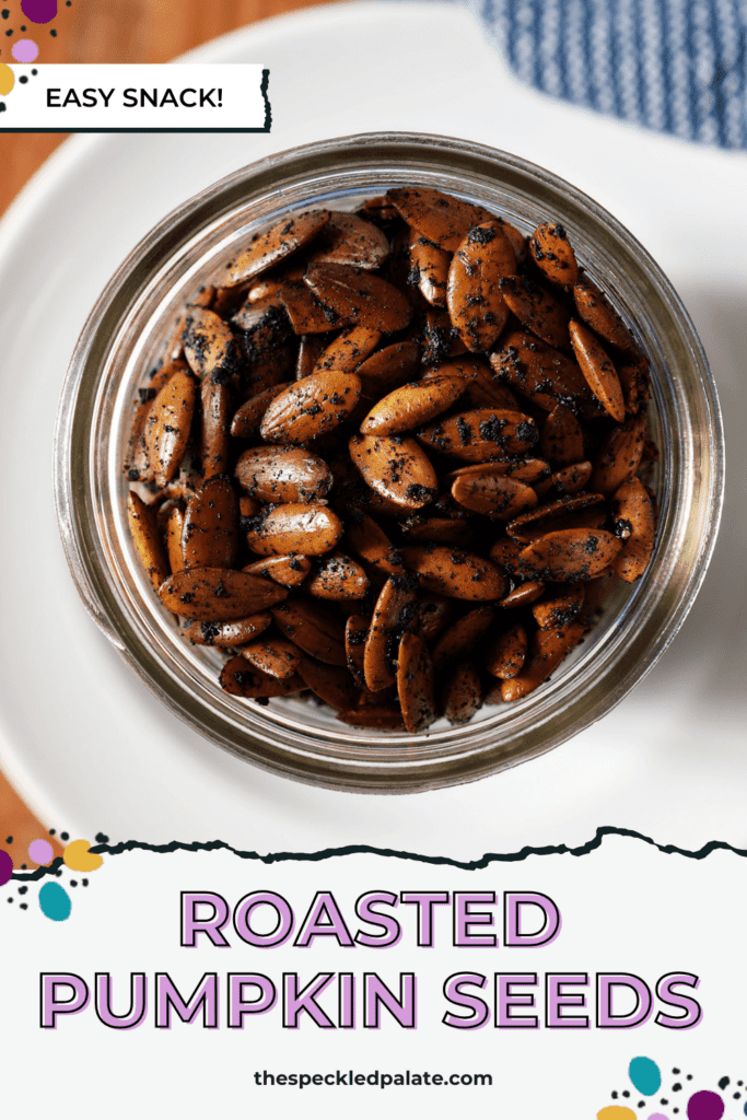 Close up of roasted pumpkin seeds in a mason jar on a white plate with a blue towel with the text roasted pumpkin seeds