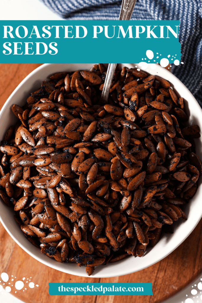 A white bowl of roasted pepitas on wood with the text roasted pumpkin seeds