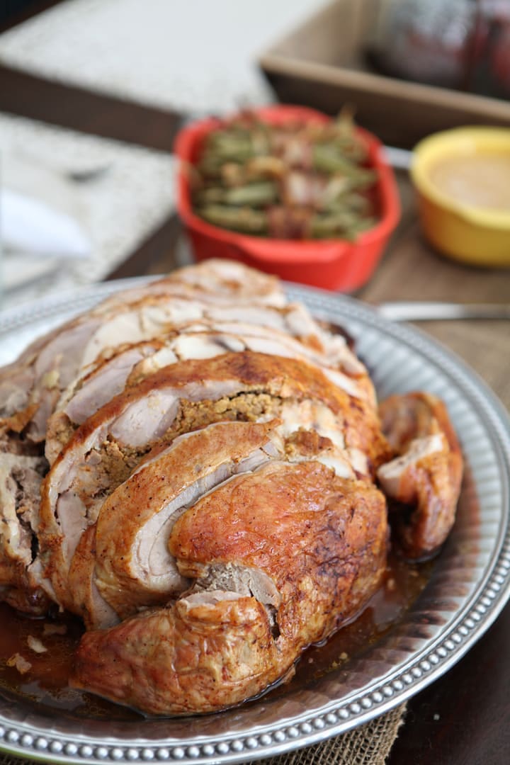 Roasted Turducken on a silver platter surrounded by side dishes 