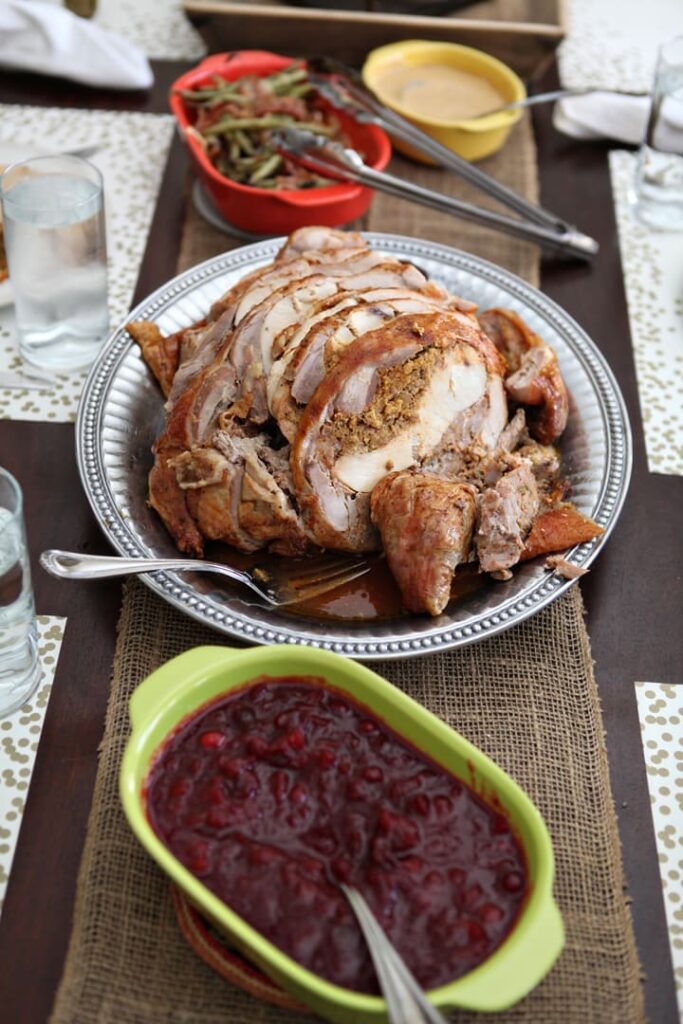 Turducken on platter next to thanksgiving side dishes on wood board 