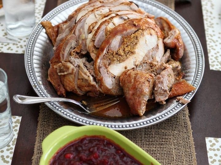 Turducken on platter next to thanksgiving side dishes on wood board