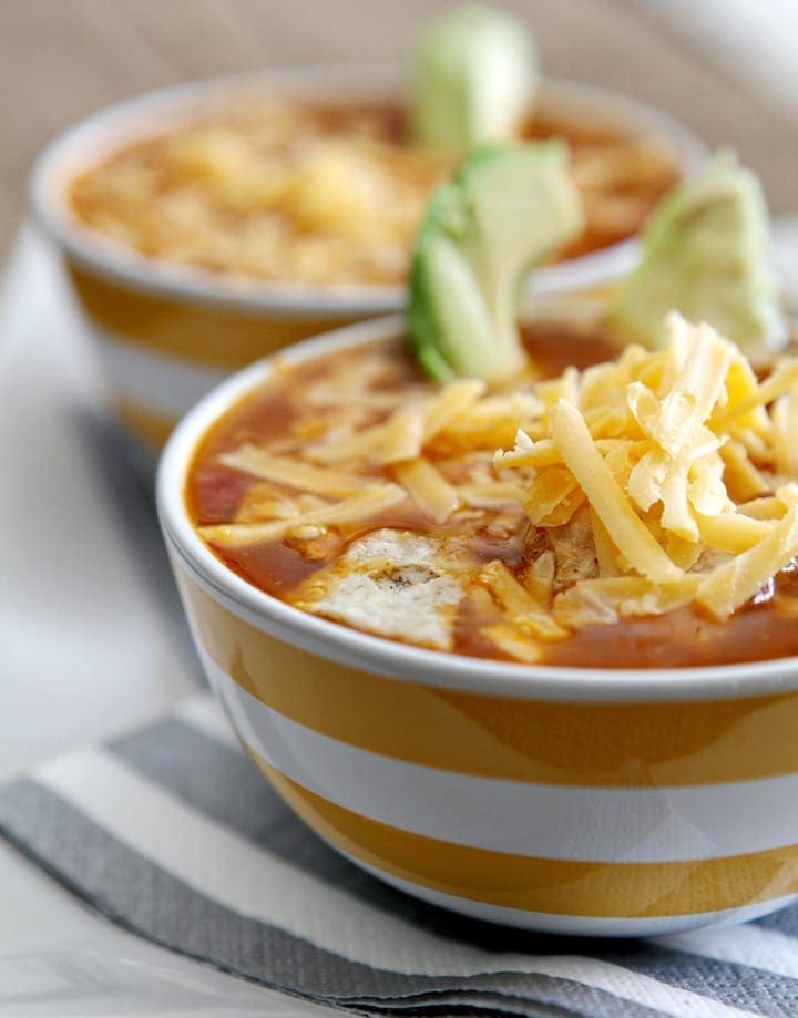 Angled view of turkey tortilla soup in two yellow and white striped bowls 