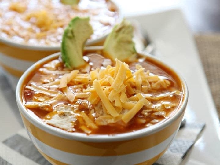 Two bowls of turkey tortilla soup on white serving dish
