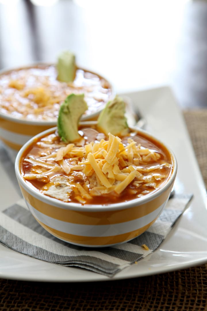 Two bowls of turkey tortilla soup on white serving dish 