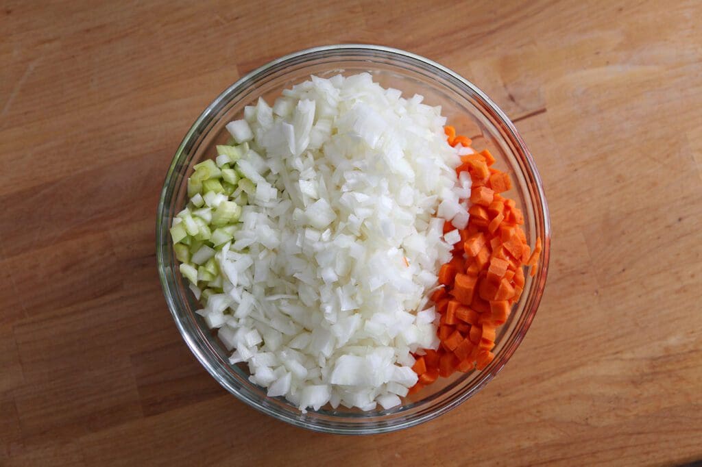 Mirepoix in a glass bowl on a golden wooden table