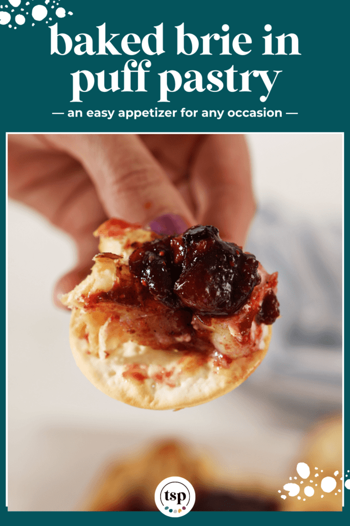 A hand holds a cracker slathered with Baked Brie and cranberry chutney with the text Baked Brie in puff pastry an easy appetizer for any occasion