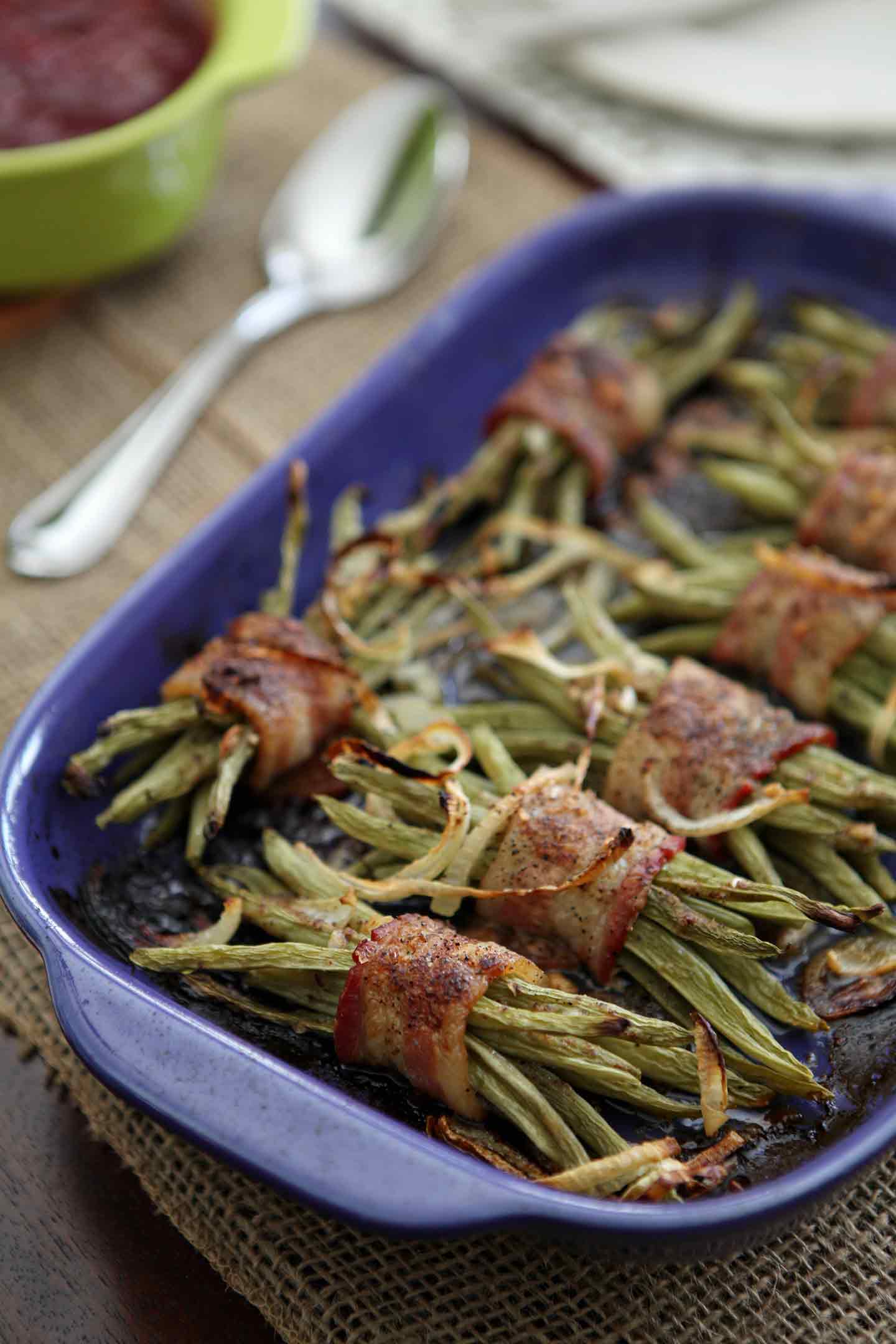 A platter of Green Bean Bacon Bundles sits on a Thanksgiving table