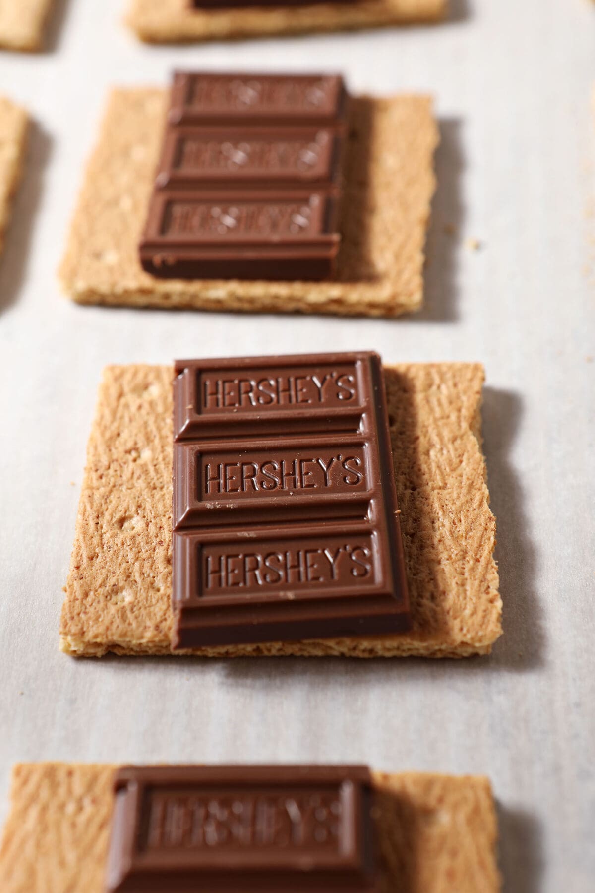 Chocolate bars on top of Graham crackers on a sheet pan