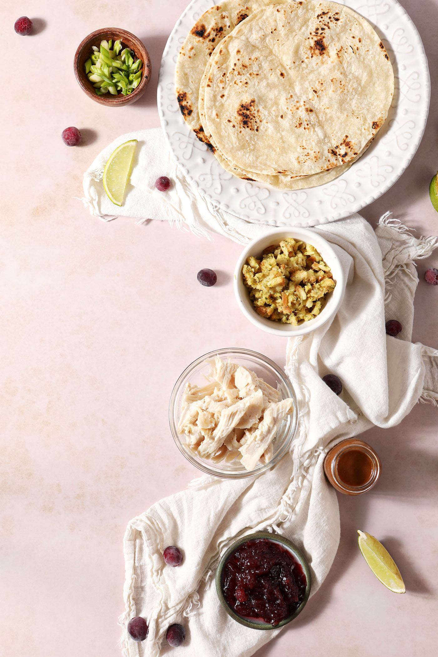 Ingredients to make tacos out of thanksgiving leftovers in bowls and plates on a pinkish brown surface