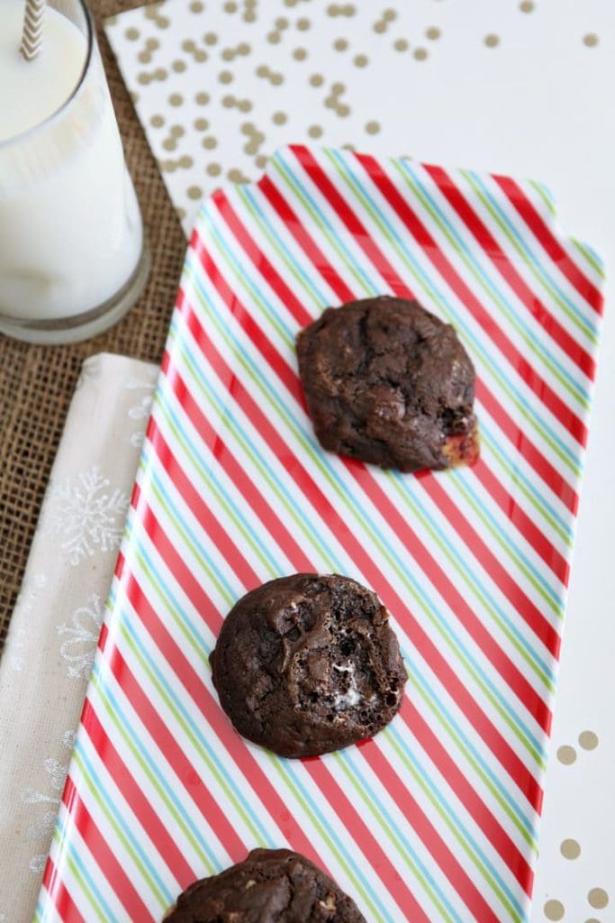 Overhead of Chocolate Marshmallow Cookies with Pecans on a red, green and white striped platter by a glass of milk