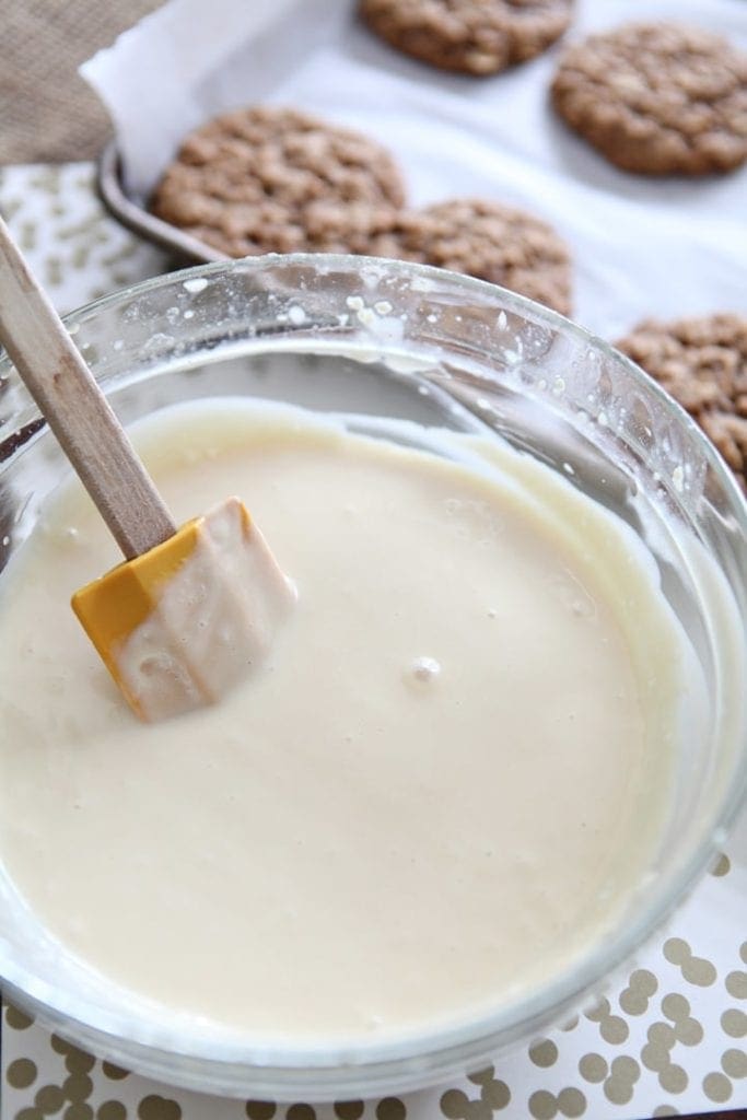 Yellow spatula resting inside a bowl of cream cheese glaze