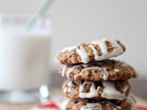 Iced Christmas cookies stacked on napkin next to glass of milk
