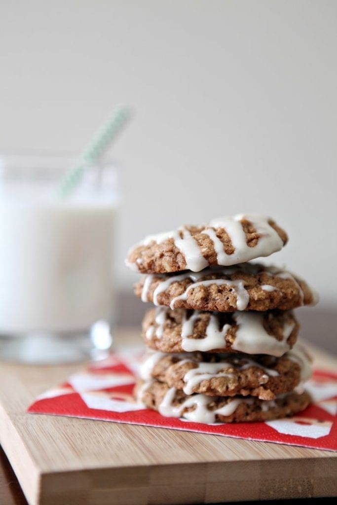 Iced Christmas cookies stacked on napkin next to glass of milk