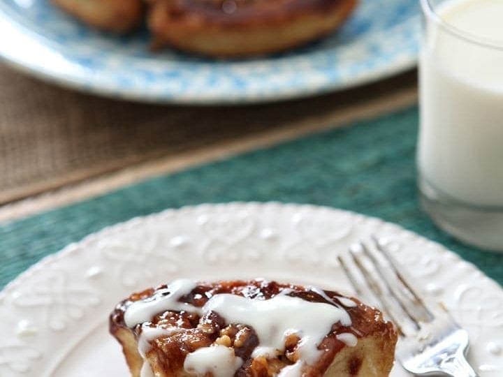 Piece of walnut sticky bun served on white plate with fork