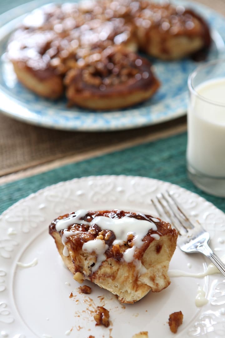 Piece of walnut sticky bun served on white plate with fork 