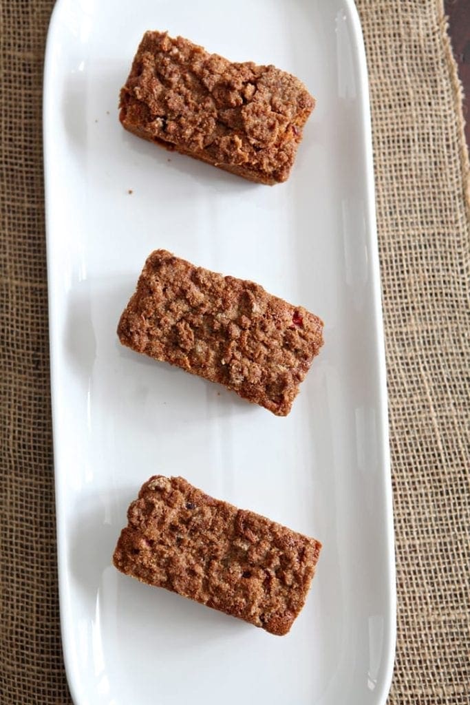 Overhead view of three pieces of cranberry walnut bread on white serving dish 