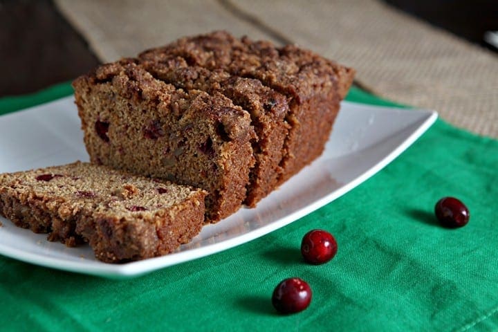 Sliced cranberry walnut bead on white serving dish on top of green linens 