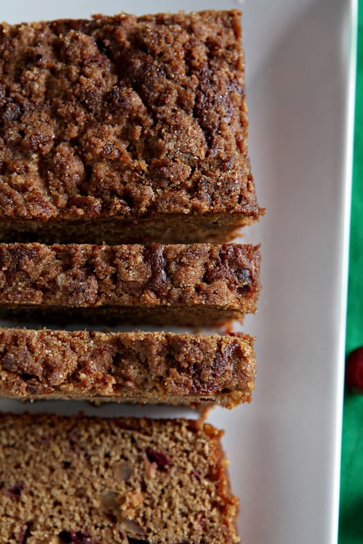 Overhead close up of sliced cranberry walnut bread on white serving dish 