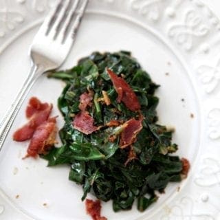 Bacon Collard Greens, served on a white plate, and topped with additional bacon