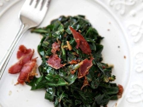 Bacon Collard Greens, served on a white plate, and topped with additional bacon