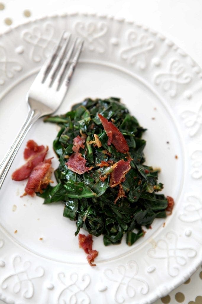 Bacon Collard Greens, served on a white plate, and topped with additional bacon