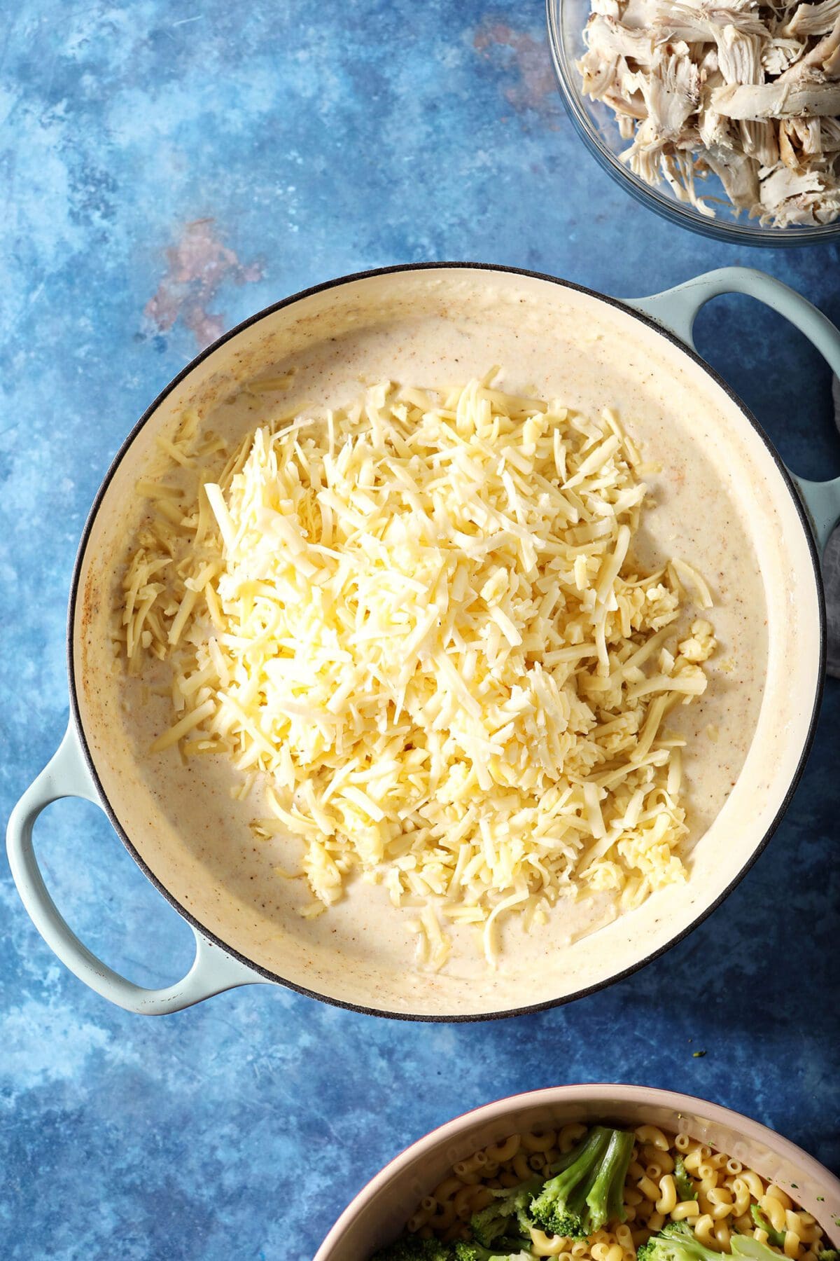 Shredded white cheese is added to the sauce for macaroni and cheese