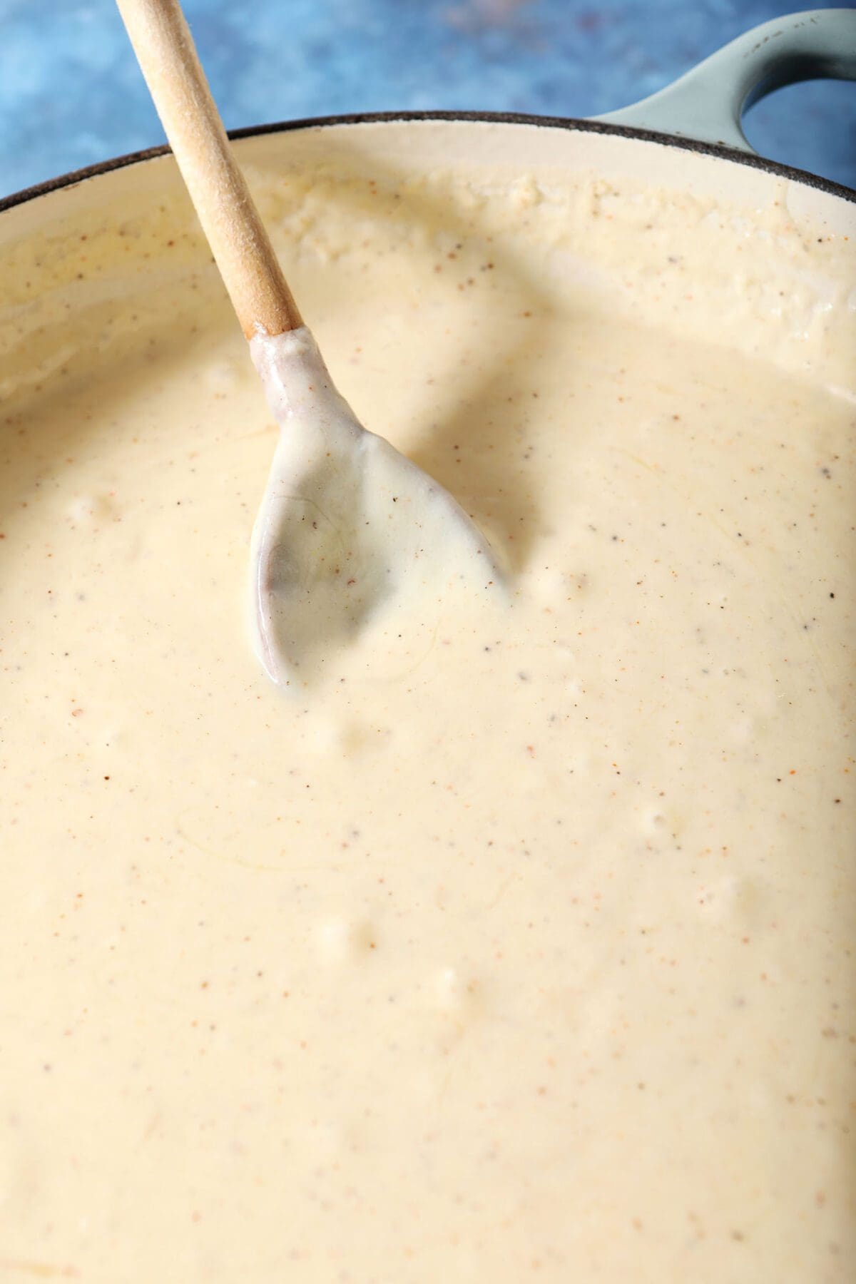 Close up of cheesy macaroni and cheese sauce with a wooden spoon