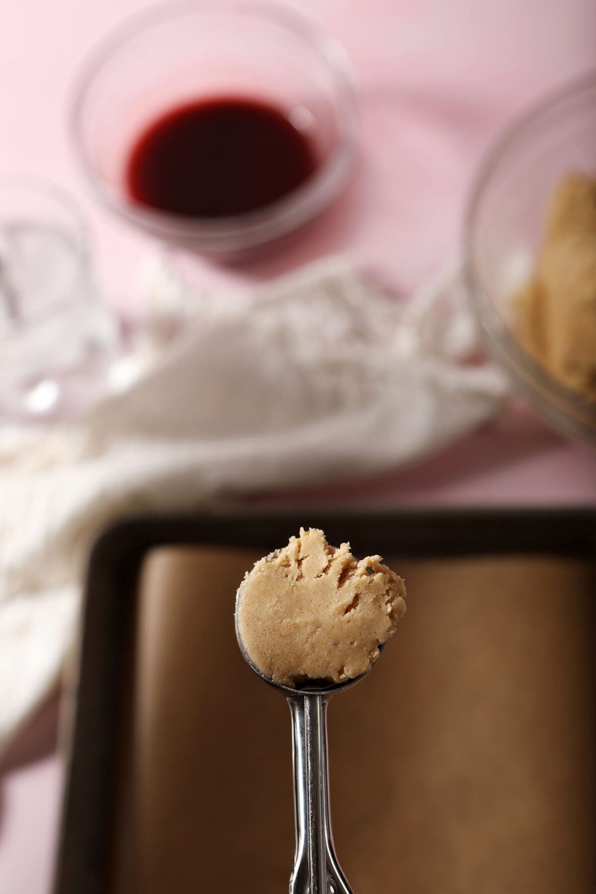 A cookie scoop of peanut butter shortbread cookie dough above a baking sheet