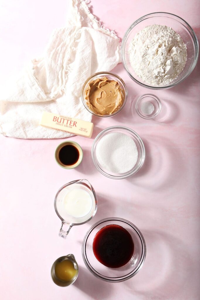 Ingredients to make peanut butter shortbread and a raspberry glaze on a pink countertop