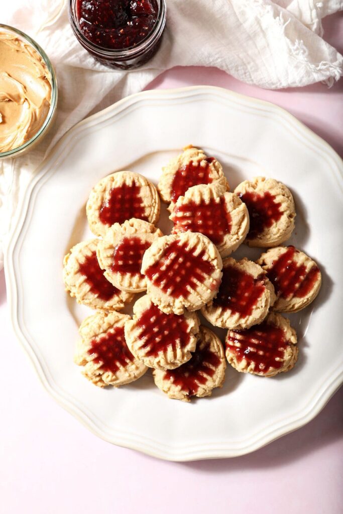 A platter of Peanut Butter Shortbread Cookies with raspberry glaze on a pink countertop