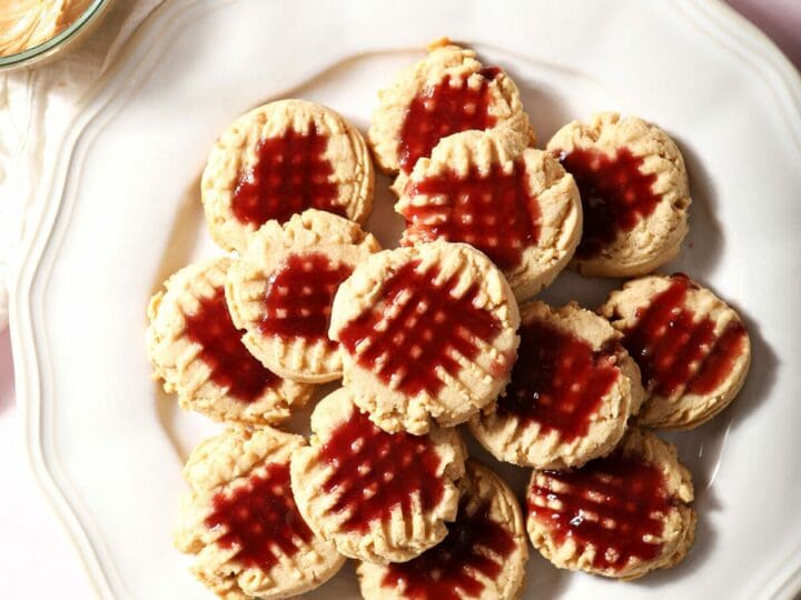 A platter of Peanut Butter Shortbread Cookies with raspberry glaze on a pink countertop