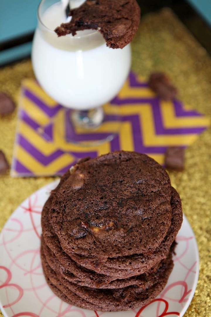 Stack of cookies on a plate next to glass of milk 