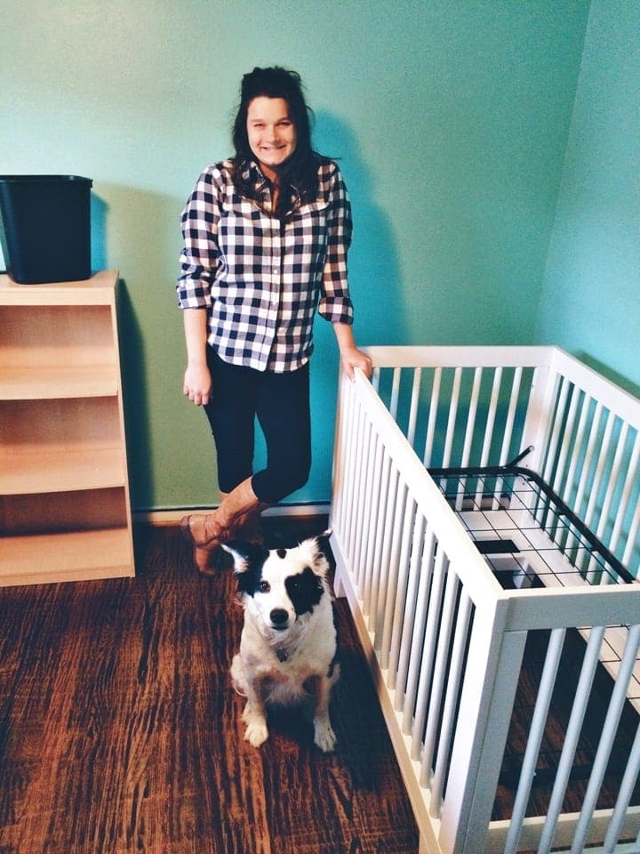 A woman and a dog standing next to a white crib 