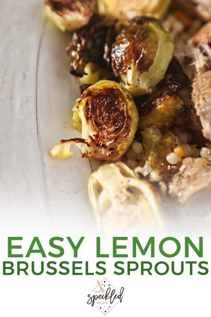 Close up of roasted brussels sprouts on a white serving tray with meat and couscous with the text 'easy lemon brussels sprouts'