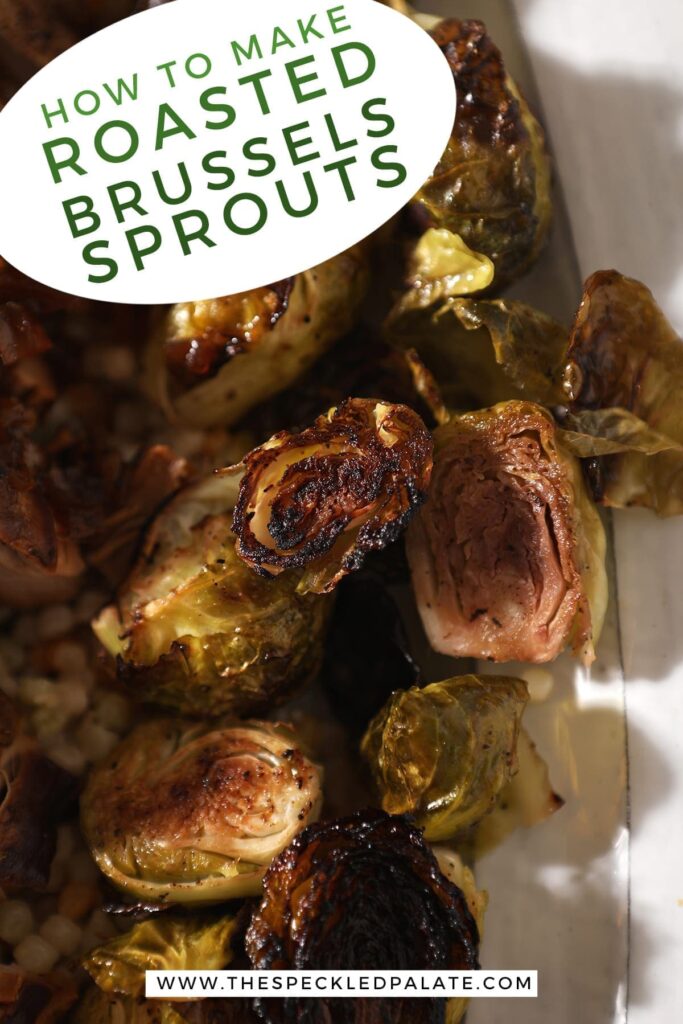 Close up of roasted brussels sprouts on a white serving tray with meat and couscous with the text 'how to make roasted brussels sprouts'