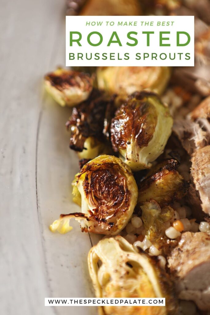 Close up of roasted brussels sprouts on a white serving tray with meat and couscous with the text 'how to make the best roasted brussels sprouts'